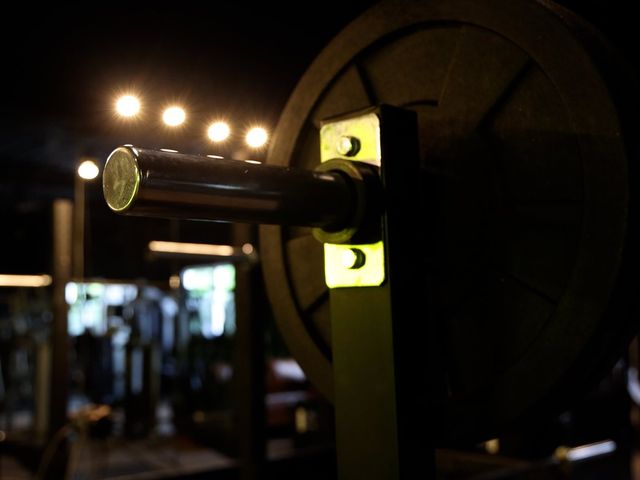 A loaded barbell racked in the half light, floor lights behind it