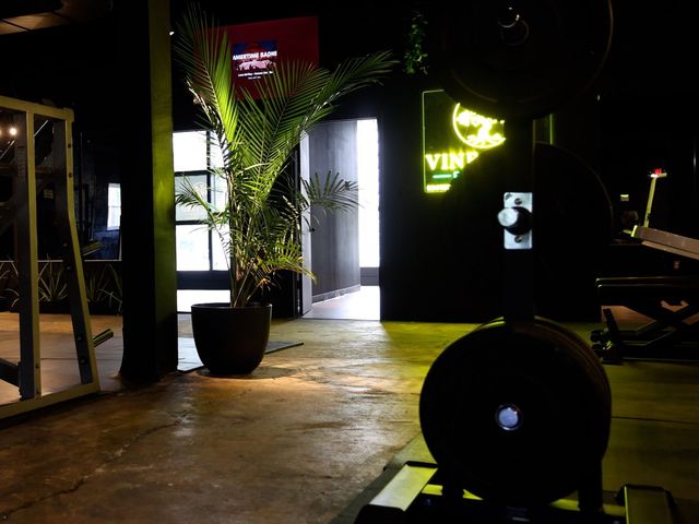 Racks, machines and a loaded barbell in place on the Vine Yard Fitness floor, lit by the entrance and the neon sign